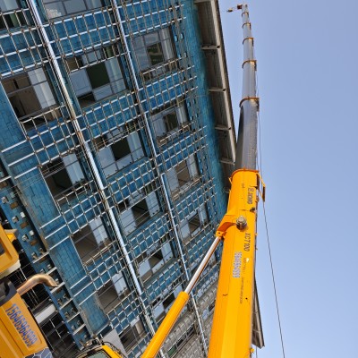 如何通过改进吊具如使用平衡梁，来解决双机抬吊的同步问题？